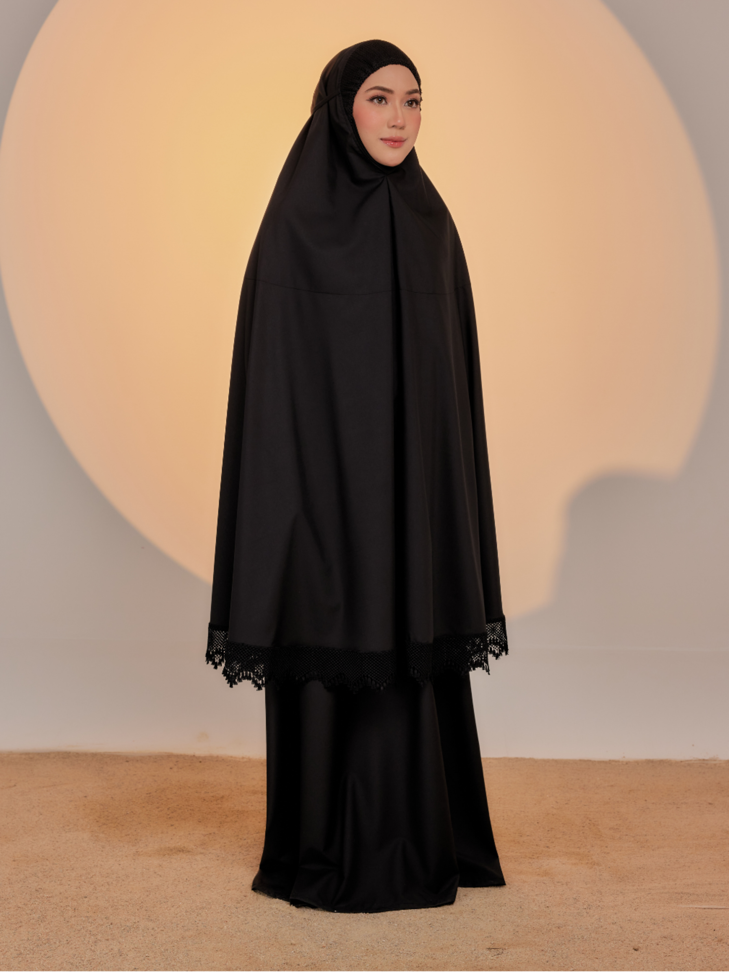 Woman wearing a black abaya against a neutral background